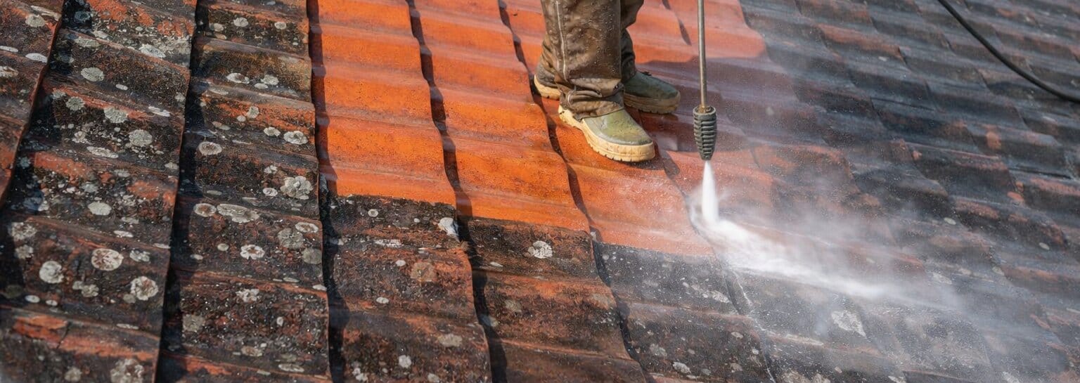 Man Power Washing A Tile Roof Wide Angle